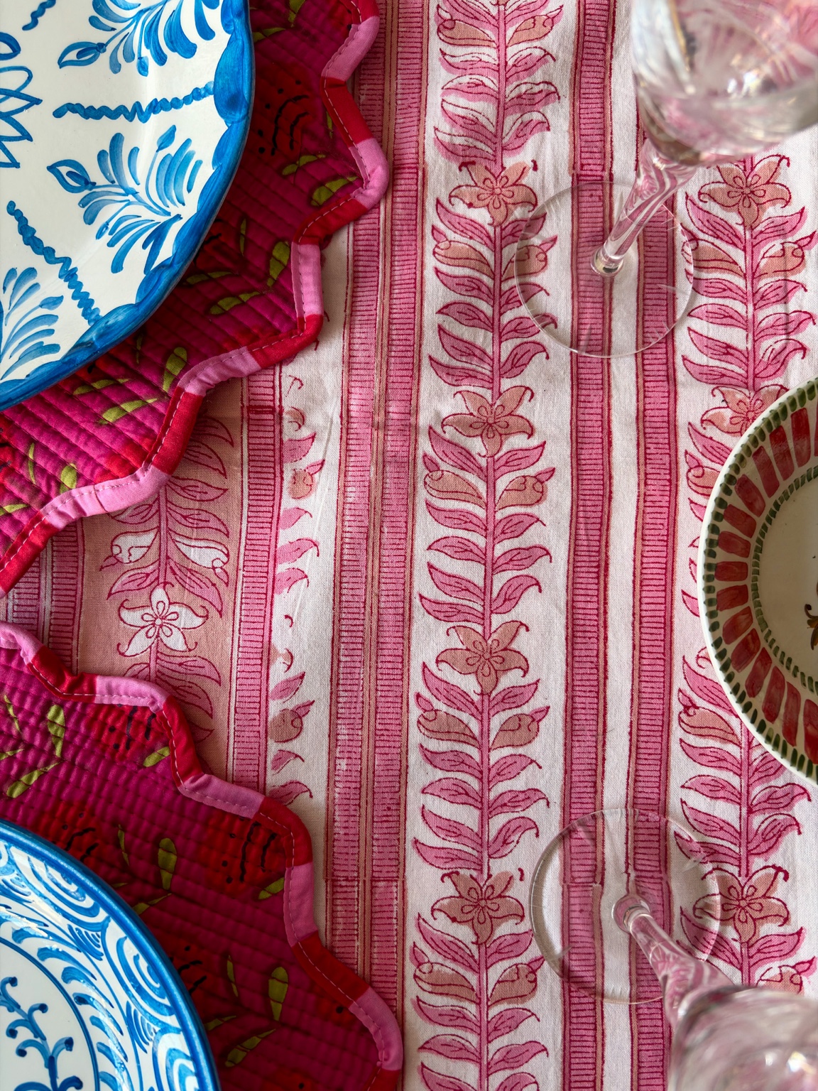 Detalle de mantel estampado rosa, individuales con festones y vajilla azul